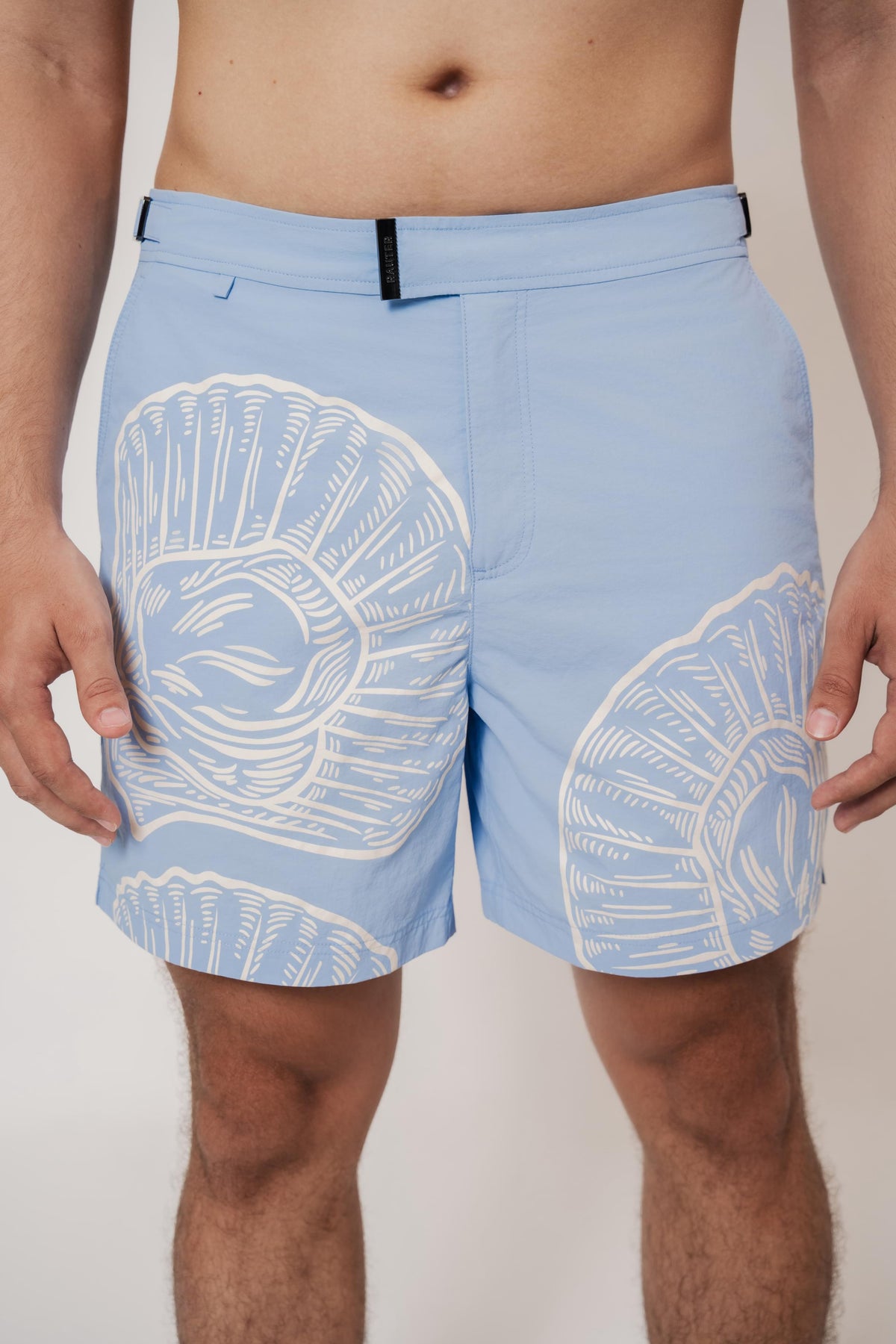 Detalhe da cintura do short RAUTER CONCHAS MÉDIO com fivela ajustável em estampa sublimada de conchas do mar.