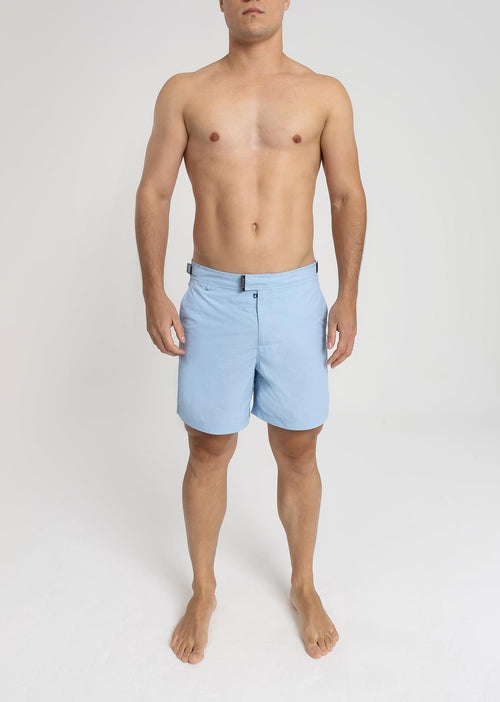 Modelo usando o short de praia RAUTER AZUL BEBÊ MÉDIO, nylon reciclado, corte médio.