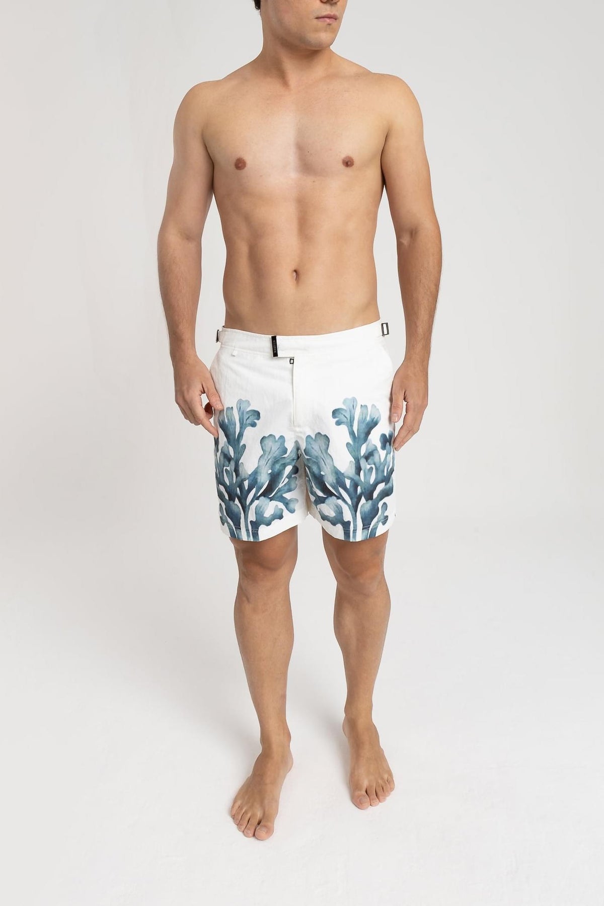 Modelo usando o short de praia RAUTER ALGAS MARINHAS MÉDIO, estampa sublimada de algas marinhas em aquarela, corte médio.