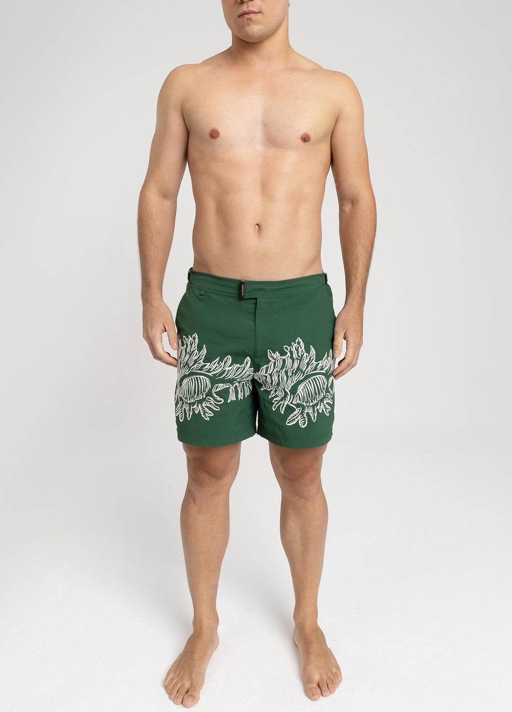 Modelo usando o short de praia RAUTER CORAIS MÉDIOS, bordado industrial de corais sobre nylon reciclado, corte médio.