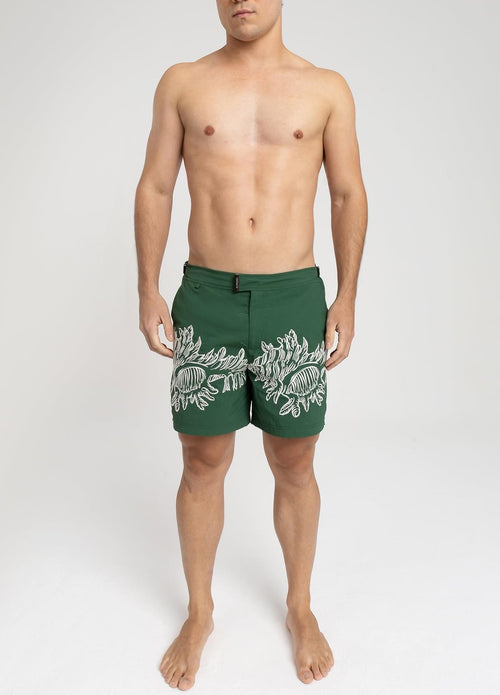 Modelo usando o short de praia RAUTER CORAIS MÉDIOS, bordado industrial de corais sobre nylon reciclado, corte médio.