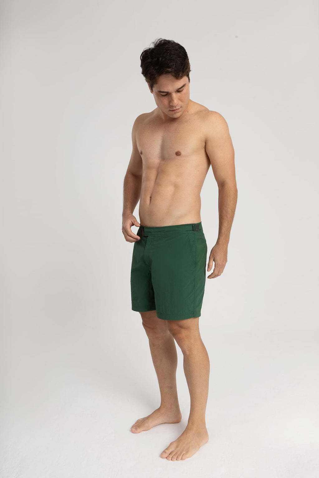 Homem usando short de praia RAUTER VERDE MÉDIO, com nylon reciclado e estilo sofisticado.