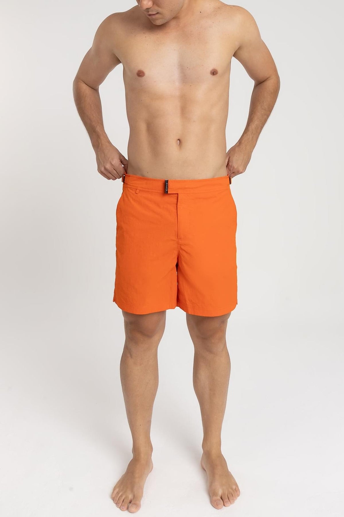 Homem usando short de praia RAUTER LARANJA MÉDIO, com nylon reciclado e estilo sofisticado.