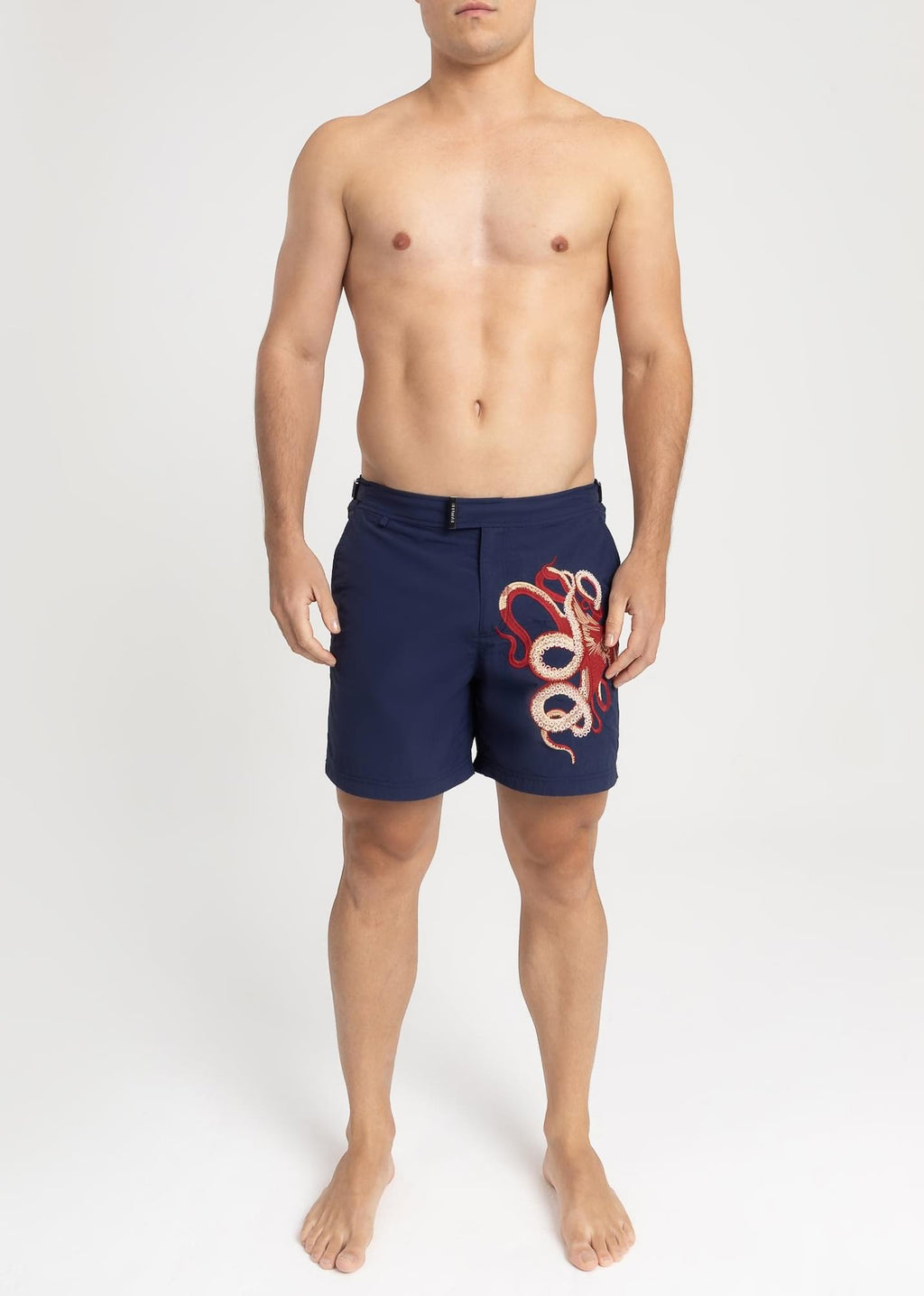 Modelo usando o short de praia RAUTER POLVO MÉDIO, bordado industrial de polvo sobre nylon reciclado, corte médio.